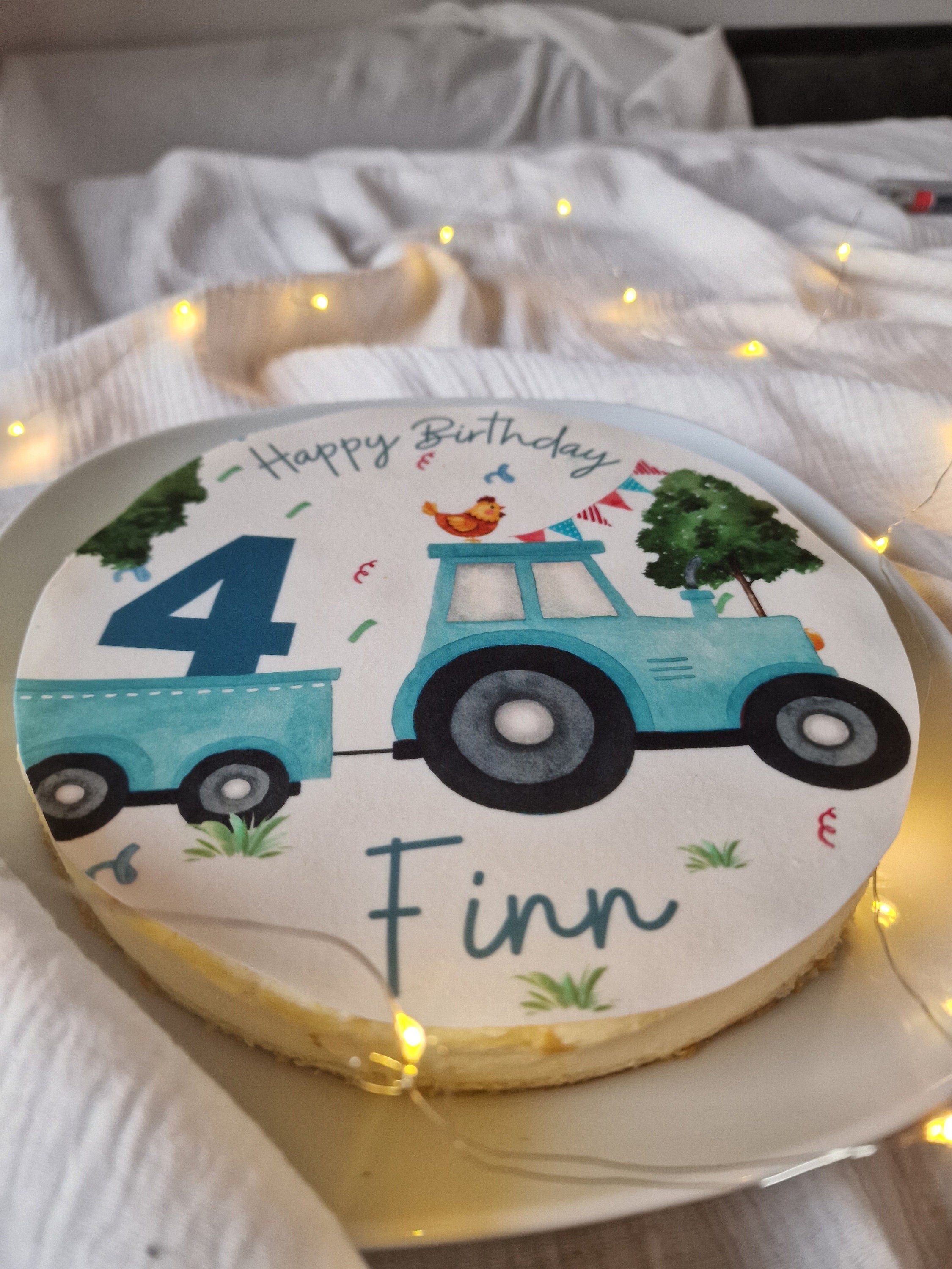 Essbarer Tortenaufleger mit Traktor-Motiv, personalisiert mit Name und Alter, auf einer Geburtstagstorte für Kinder.