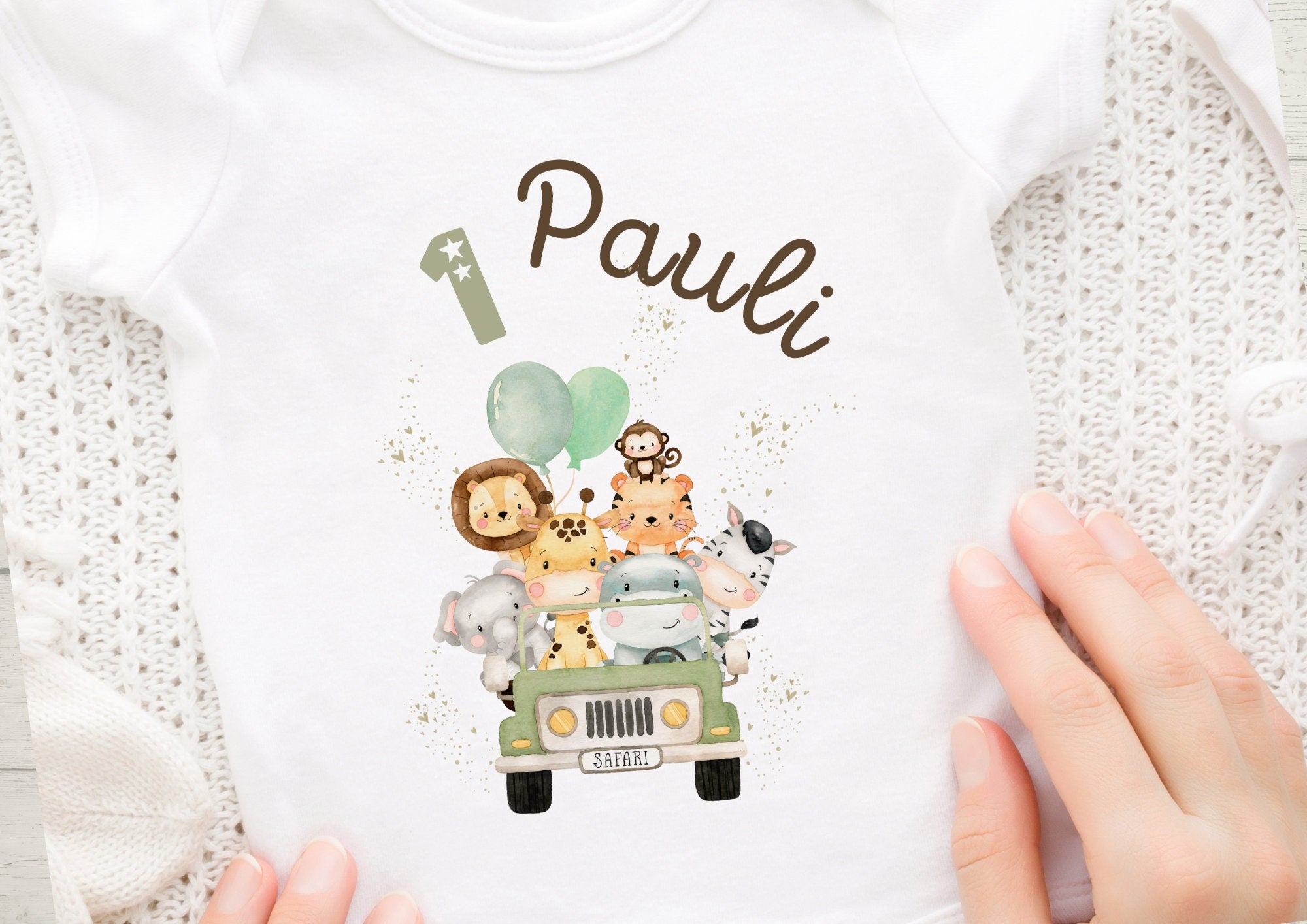 Personalisierbares Bügelbild mit Dschungeltieren und Auto für Kindergeburtstag
Bügelbild Wild One mit Wunschname und Alter im Safari-Stil
Aufgebügeltes Motiv mit Zebra, Löwe und Auto auf Kinder-Shirt
Nahaufnahme des Jungle-Bügelmotivs mit Palmen und Geburtstagszahl
Beispielanwendung des Bügelbildes auf hellem T-Shirt
