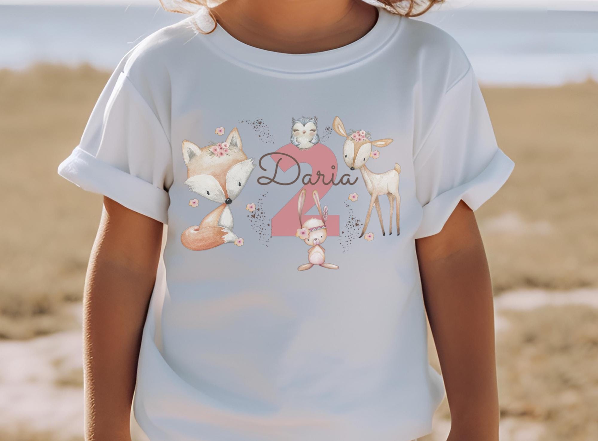 Kind trägt weißes Geburtstagsshirt mit rosa Waldtieren – personalisiert mit Name und Zahl – Motiv: Reh, Bär, Eule, Blumen