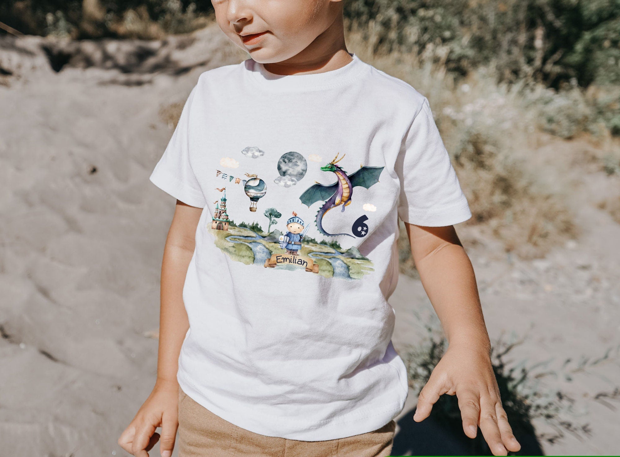 Kind trägt weißes T-Shirt mit buntem Ritter-Motiv und Drache – personalisiert mit Name und Zahl zum Geburtstag